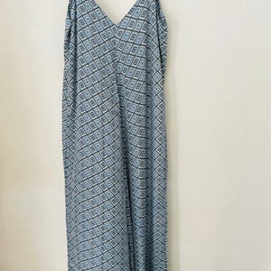 May include: A long, blue and white patterned maxi dress with thin straps and a V-neckline.