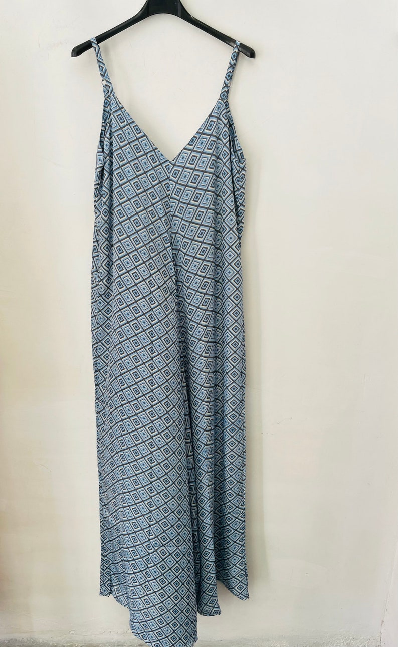 May include: A long, blue and white patterned maxi dress with thin straps and a V-neckline.