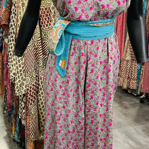 May include: A floral print jumpsuit with a turquoise sash. The jumpsuit has a sleeveless top and wide-legged pants.