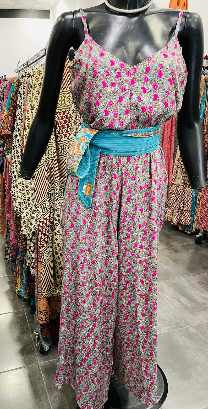 May include: A floral print jumpsuit with a turquoise sash. The jumpsuit has a sleeveless top and wide-legged pants.