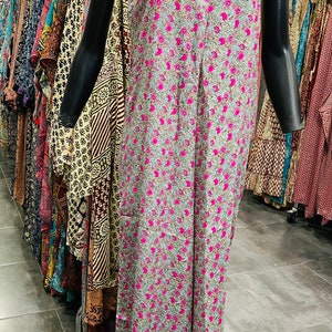 May include: A long, sleeveless, pink and blue floral print dress with a V-neckline. The dress is on a mannequin in a clothing store.