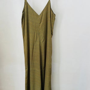 May include: A long, green sleeveless dress with a geometric pattern. The dress has a V-neckline and a relaxed fit.