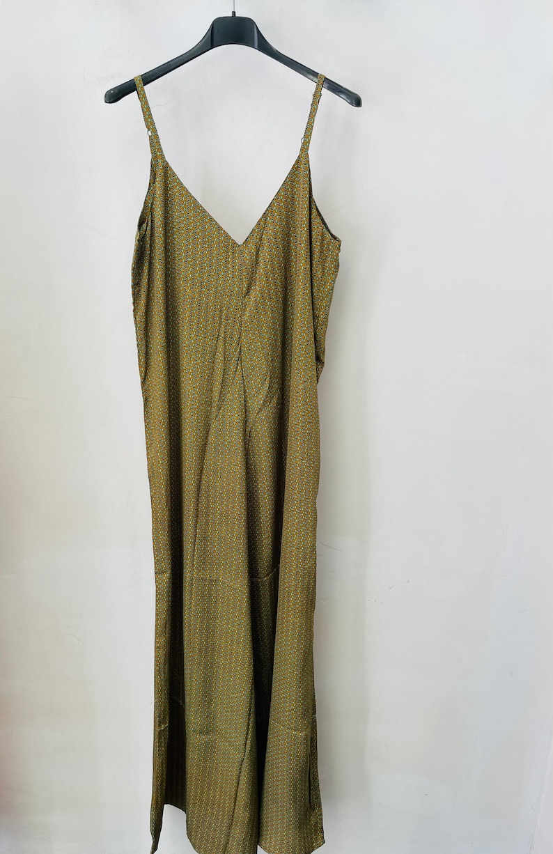 May include: A long, green sleeveless dress with a geometric pattern. The dress has a V-neckline and a relaxed fit.