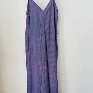 May include: A long, sleeveless, purple dress with a small, white and pink geometric pattern. The dress has a V-neckline and thin straps.