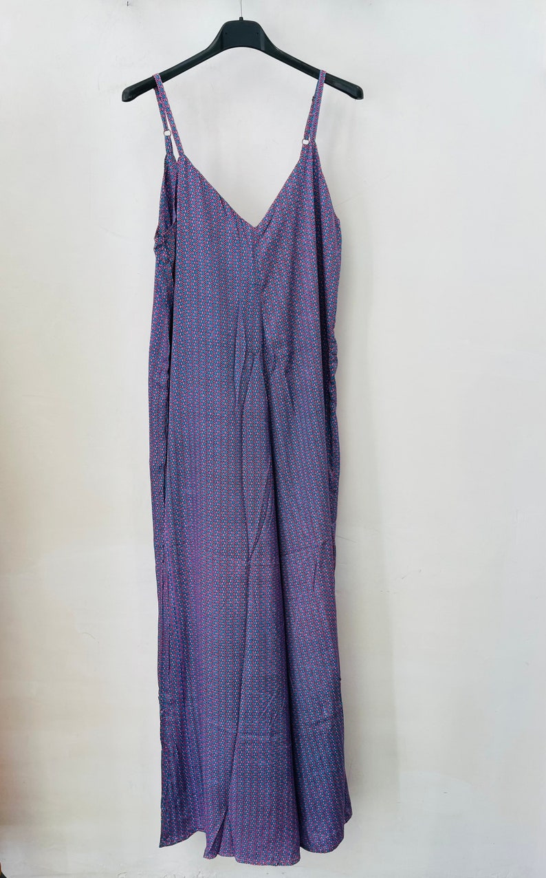 May include: A long, sleeveless, purple dress with a small, white and pink geometric pattern. The dress has a V-neckline and thin straps.