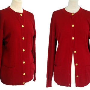 May include: A red cardigan sweater with gold buttons and two pockets. The cardigan is shown from the front and back.