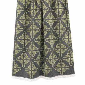 May include: A rectangular textile throw featuring a dark charcoal gray base color with a repeating light lime green damask pattern. The fabric has a visible woven texture and is finished with a short white fringe along the bottom edge.