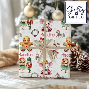 May include: White Christmas wrapping paper with a Nutcracker, gingerbread people, mice, and reindeer. The paper is decorated with snowflakes and candy canes. The name "Madeline" is repeated throughout the design.