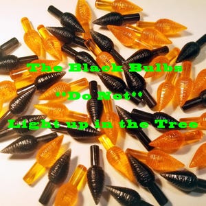 May include: A close-up of a pile of orange and black Christmas light bulbs. The bulbs are shaped like a teardrop and have a textured surface. The text "The Black Bulbs "Do Not" Light Up In The Tree" is written on the image.