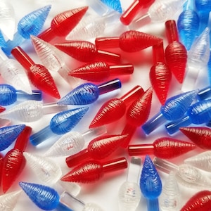 May include: A collection of red, white, and blue Christmas light bulb covers. The covers are shaped like a teardrop and have a textured surface.