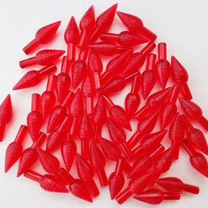 May include: A pile of 50 red, clear, plastic Christmas tree light bulbs with a textured, ribbed design. The bulbs are shaped like a teardrop with a pointed tip.