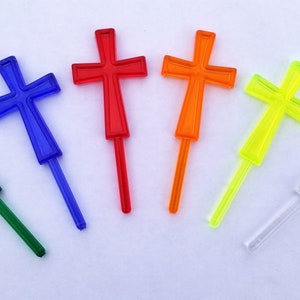 May include: Six plastic crosses in different colors: green, blue, red, orange, yellow, and clear. The crosses are on a white background.