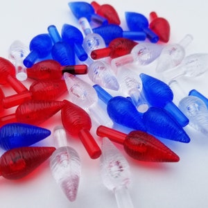 May include: A collection of red, white, and blue Christmas light bulb covers. The covers are shaped like a teardrop and have a textured surface.