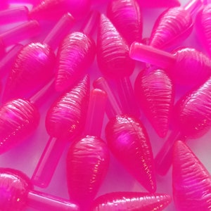 May include: A group of bright pink plastic Christmas tree ornaments with a textured, ribbed surface. The ornaments are shaped like a teardrop with a pointed tip and a small hole at the top for hanging.