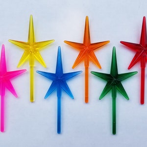 May include: Assortment of ten star-shaped Christmas tree toppers in various colors, including clear, yellow, pink, blue, orange, red, green, and purple.