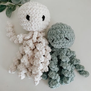 Puede incluir: Dos peluches de pulpo tejidos a crochet, uno en blanco y otro en verde azulado. Ambos tienen ojos negros y est&aacute;n hechos con un hilo suave y esponjoso.