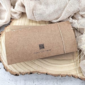 May include: A brown paper envelope with a string tied around it. The envelope has a QR code and the text "at Love for the Handmade" printed on it.