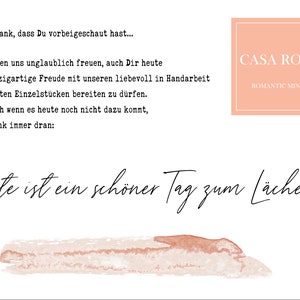 May include: A watercolor illustration of a pink and orange brushstroke with the text "Heute ist ein sch&ouml;ner Tag zum L&auml;cheln!" in black cursive. The text "CASA ROMI" and "ROMANTIC MINDS" are in a white sans-serif font on a pink rectangle.