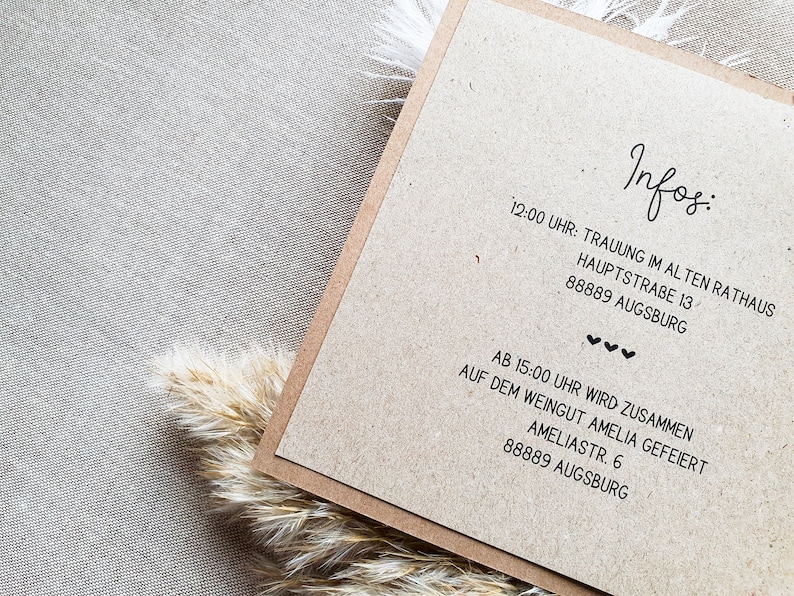 May include: A brown card with the text "Infos:" and details for a wedding ceremony and reception. The ceremony will be held at the Old Town Hall, Hauptstra&szlig;e 13, 88889 Augsburg, at 12:00 PM. The reception will be held at the Amelia Winery, Amelia Str. 6, 88889 Augsburg, at 3:00 PM.