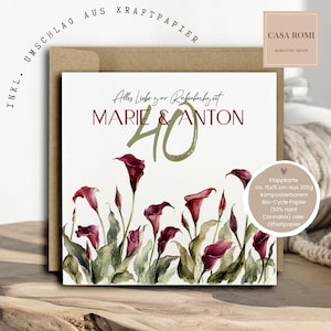 Könnte beinhalten: Eine quadratische Grußkarte mit weißem Hintergrund und einer Aquarellillustration aus dunkelroten Calla-Lilien und grünen Blättern. Der Text lautet Alles Liebe zur Rubinhochzeit, MARIE & ANTON und 40 Jahre. Dahinter befindet sich ein brauner Kraftpapierumschlag.
