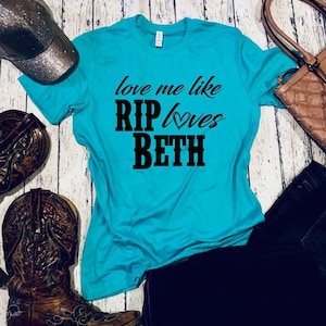 Könnte beinhalten: Türkisfarbenes T-Shirt mit schwarzem Text, der "Love me like RIP loves Beth" mit einem Herzsymbol lautet.