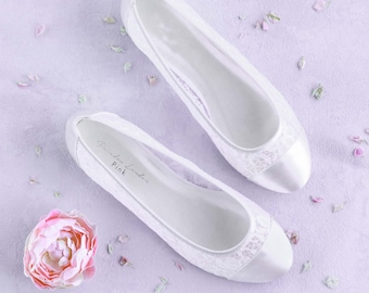 Puede incluir: Un par de zapatos de novia de encaje blanco con punteras de satén. Los zapatos tienen un delicado patrón de encaje y son perfectos para una boda.