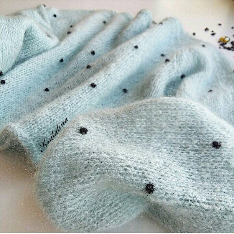 May include: A light blue knitted sweater with black polka dots. The sweater is made of a soft, fuzzy yarn.