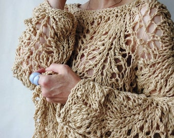 May include: A beige crochet sweater with a loose, open-weave design. The sweater has a wide neckline and long sleeves.