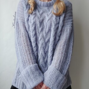 Peut inclure: Un pull en maille torsad&eacute;e bleu clair &agrave; la coupe ample et aux manches longues. Le pull pr&eacute;sente un motif textur&eacute; et une allure l&eacute;g&egrave;rement surdimensionn&eacute;e.