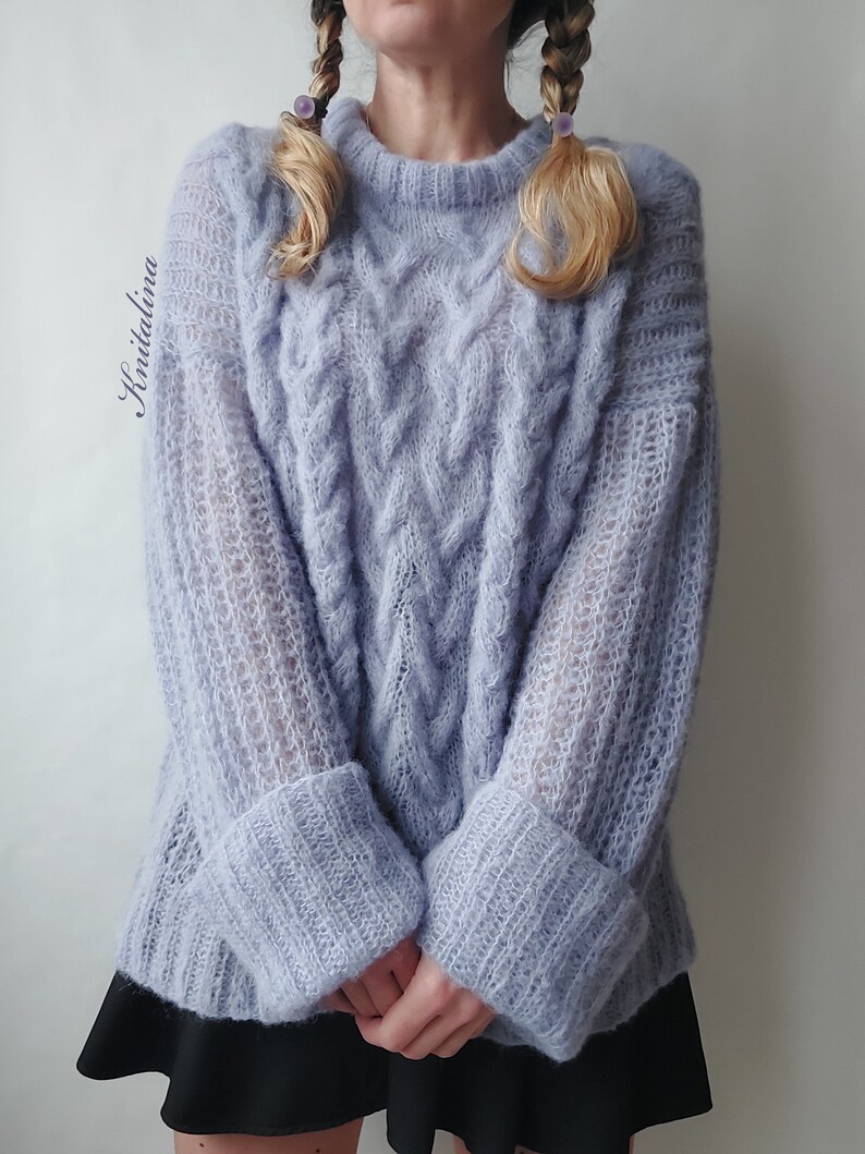 Peut inclure: Un pull en maille torsad&eacute;e bleu clair &agrave; la coupe ample et aux manches longues. Le pull pr&eacute;sente un motif textur&eacute; et une allure l&eacute;g&egrave;rement surdimensionn&eacute;e.
