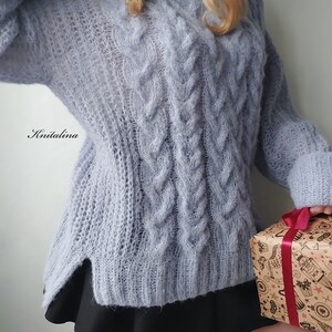 Peut inclure: Un pull en maille torsad&eacute;e bleu clair &agrave; la coupe ample et l&eacute;g&egrave;rement surdimensionn&eacute;e. Le pull est fait d'un fil doux et moelleux et a un style d&eacute;contract&eacute; et d&eacute;tendu.