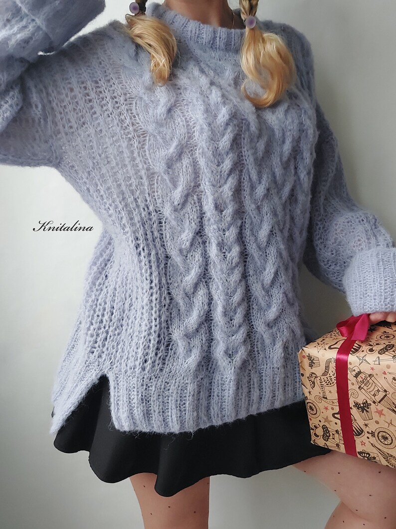 Peut inclure: Un pull en maille torsad&eacute;e bleu clair &agrave; la coupe ample et l&eacute;g&egrave;rement surdimensionn&eacute;e. Le pull est fait d'un fil doux et moelleux et a un style d&eacute;contract&eacute; et d&eacute;tendu.