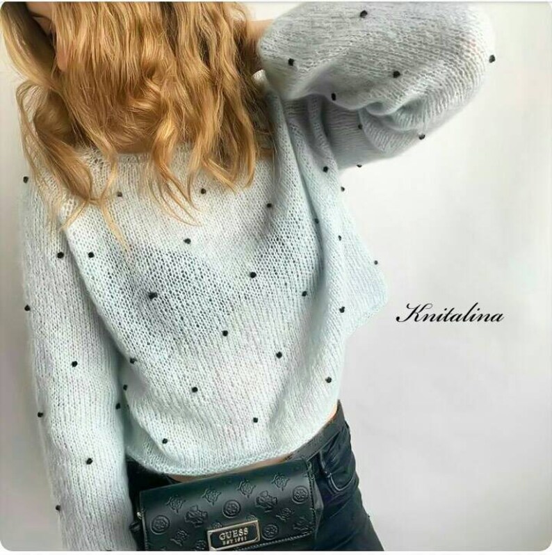May include: A light blue knitted jumper with black beads throughout. The jumper has a relaxed fit and a slightly cropped length. The jumper is worn with black jeans and a black belt.