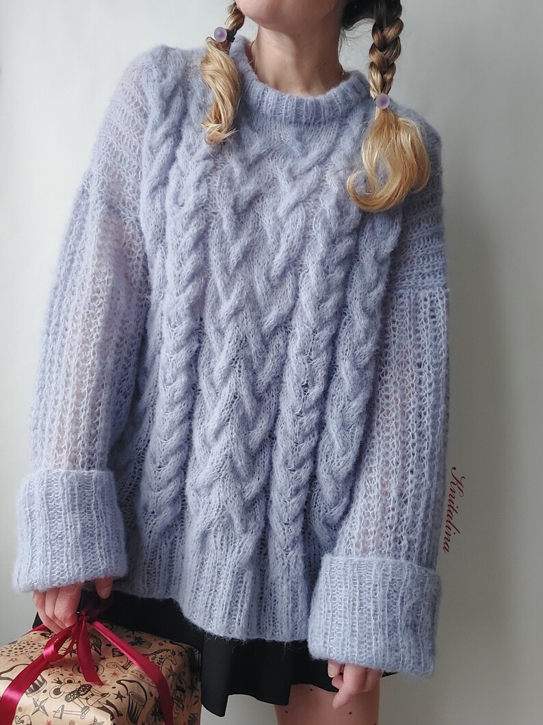 Peut inclure: Un pull en maille torsad&eacute;e surdimensionn&eacute; bleu clair &agrave; manches longues et &agrave; la coupe ample. Le pull a un aspect textur&eacute; et duveteux et pr&eacute;sente un motif en maille torsad&eacute;e.