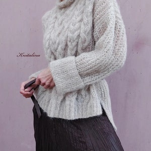 Peut inclure: Un pull en maille beige clair avec un motif en tricot torsad&eacute; et des manches longues. Le pull a une coupe ample et une longueur l&eacute;g&egrave;rement plus longue dans le dos.