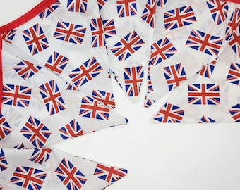 May include: White fabric bunting with a repeating pattern of the Union Jack flag. The edges are trimmed with red fabric. The bunting is ideal for patriotic celebrations and events.