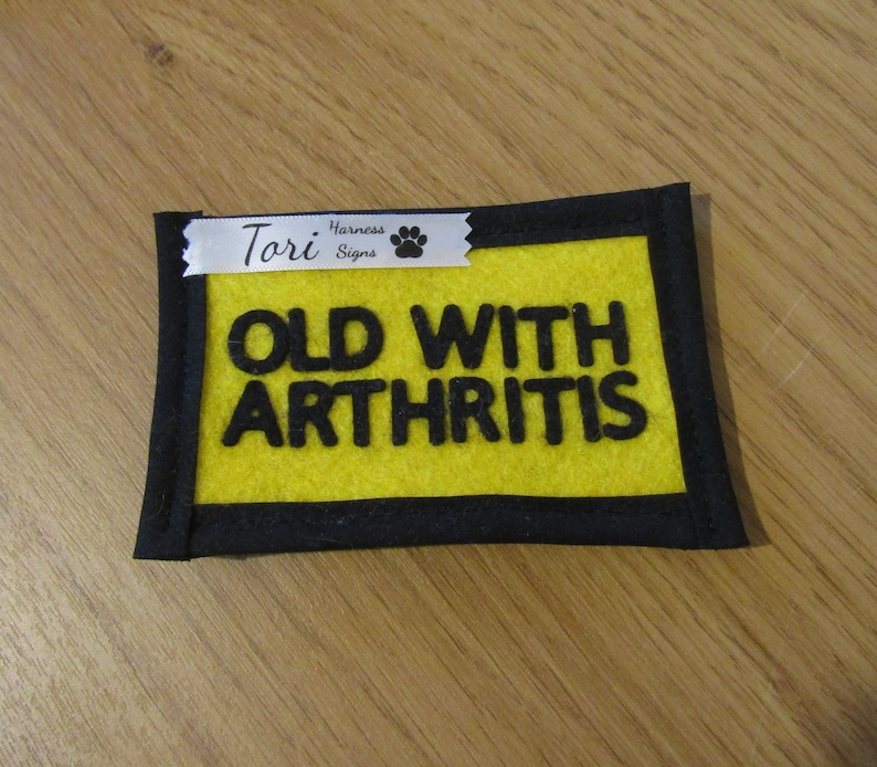 Pu&ograve; includere: Toppa per pettorina per cani in feltro giallo con testo nero che recita "Old with Arthritis" e un nastro bianco con testo nero che recita "Tori Harness Signs" e un'impronta di zampa.