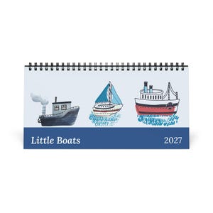 May include: A 2027 spiral-bound desk calendar titled Little Boats. The cover features illustrations of three different vessels: a dark blue steamship, a white sailboat with blue sails, and a red and white motorboat, all on a light background.