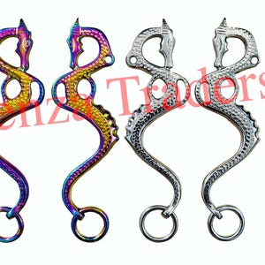 May include: Two pairs of horse bits, one pair is silver and the other is rainbow colored. Both pairs are shaped like a dragon's head.