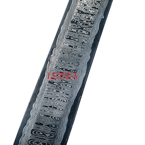 May include: A long, narrow, black and silver metal knife blank with a wavy pattern. The blank is about 10 inches long and 1.5 inches wide.