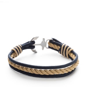 May include: A navy blue and beige rope bracelet with a silver anchor clasp.