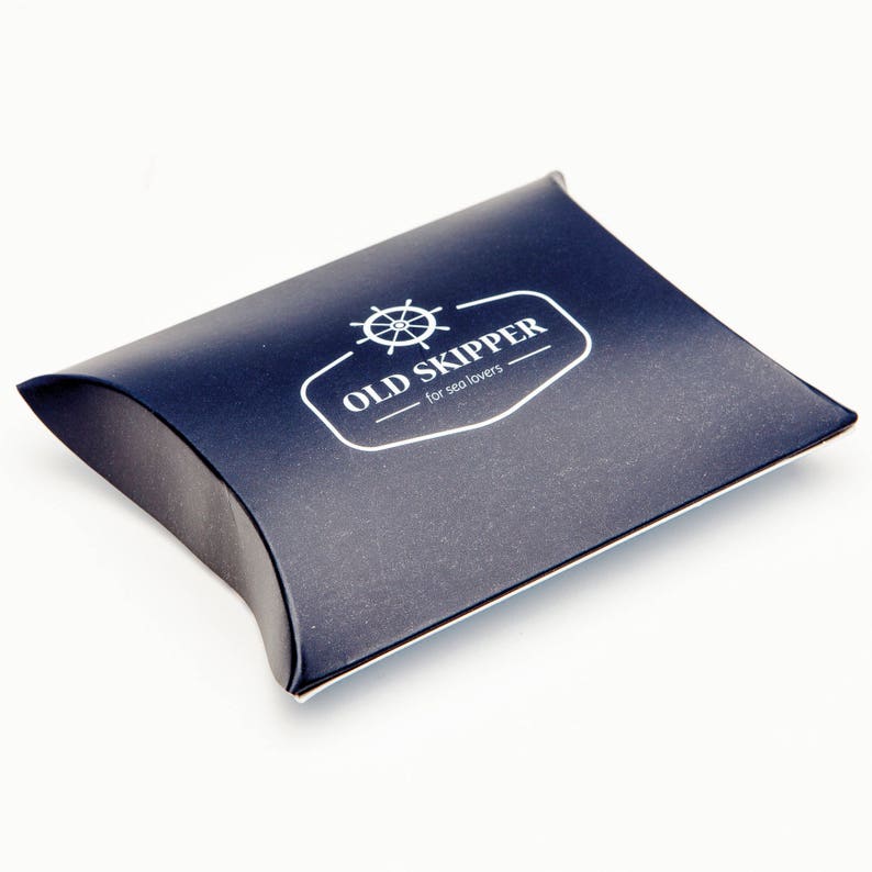 May include: A dark blue pillow box with a white logo that says "OLD SKIPPER - for sea lovers" and a nautical wheel graphic.