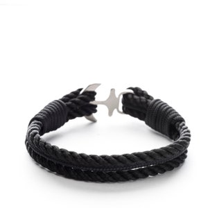 May include: A black rope bracelet with a silver anchor clasp.