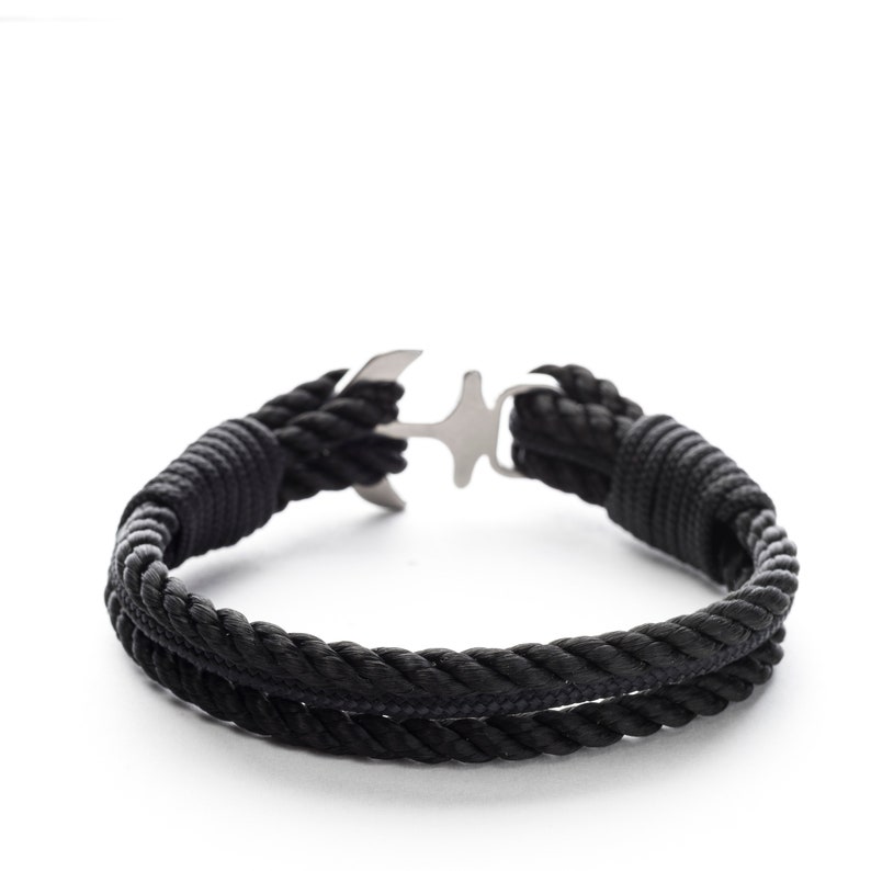 May include: A black rope bracelet with a silver anchor clasp.