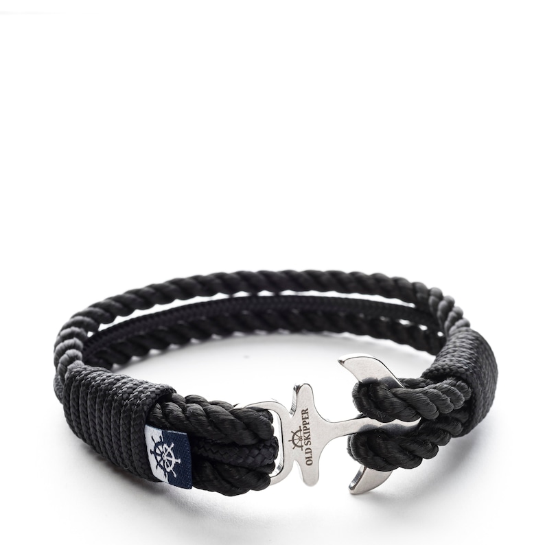 May include: Black rope bracelet with a silver anchor clasp. The anchor has the words "Old Skipper" engraved on it.