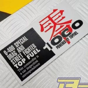 May include: A white sticker with black and red text. The text reads "0-400 SPECIAL DRAG AND STREET FIGHTER TOP FUEL 10GO POWERED BY TOPFUEL".