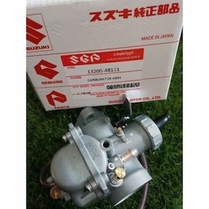 Peut inclure: Un carburateur de moto Suzuki argenté avec le numéro de pièce 13200-48111. Le carburateur est une pièce d'origine Suzuki et est fabriqué en Thaïlande.