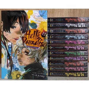May include: A collection of manga volumes, including volume 13, of the series "Hell's Paradise." The covers feature detailed illustrations of characters with vibrant colors. The spines display the series title in a stylized font.
