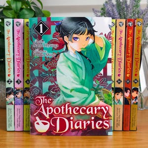 May include: A collection of The Apothecary Diaries manga volumes arranged in a row. The front-most volume features a character with dark hair in a green robe, with the title text The Apothecary Diaries and the number 1 printed on the cover.