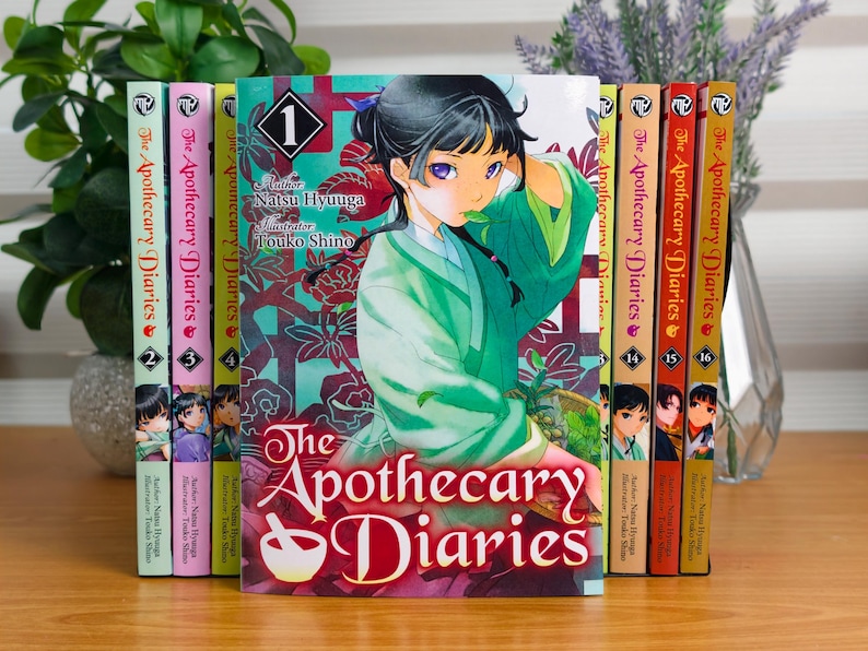 May include: A collection of The Apothecary Diaries manga volumes arranged in a row. The front-most volume features a character with dark hair in a green robe, with the title text The Apothecary Diaries and the number 1 printed on the cover.